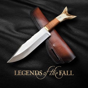 May include: A hunting knife with a brown leather sheath and a stag antler handle. The knife has a silver blade and the text "LEGENDS of the FALL" is printed below the knife.