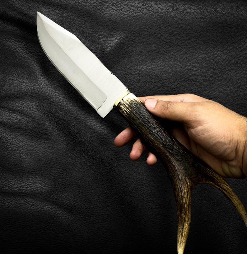 May include: A hunting knife with a stainless steel blade and a brown antler handle.