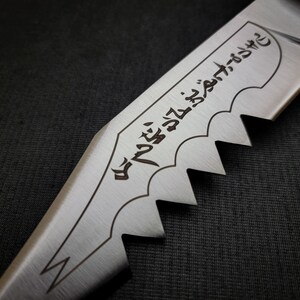 May include: Close-up of a silver knife with a serrated edge and a black inscription that reads "The blade that cuts through the darkness".