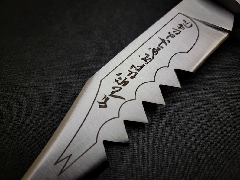 May include: Close-up of a silver knife with a serrated edge and a black inscription that reads "The blade that cuts through the darkness".