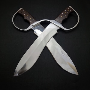 May include: Two silver blades with wooden handles crossed in an X shape against a black background.