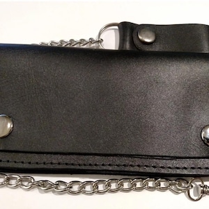 May include: Black leather wallet with a chain attached. The wallet has a flap with a snap closure and two metal studs on the front.