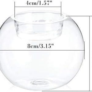 May include: A clear glass candle holder with a spherical shape. The holder has a diameter of 3.15 inches (8cm) and a height of 2.95 inches (7.5cm). The opening for the candle is 1.57 inches (4cm) wide. Ideal for home decor and events.