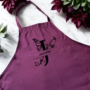 May include: Purple apron with a black butterfly and floral design, personalized with the name "Jennifer".