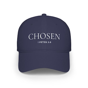 May include: A navy blue baseball cap featuring the word CHOSEN in white capital letters centred on the front panel, with the text 1 PETER 2:9 printed in a smaller white font directly underneath the main word on the crown of the hat.