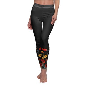 May include: Black leggings with a floral print on the lower legs. The print features red, yellow, and blue flowers.