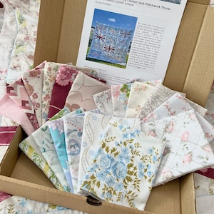 May include: A brown cardboard box containing fabric squares for a patchwork quilt. The squares are in various shades of blue, pink and white with floral patterns. The paper inside the box has a title that reads "For Quilt and Country - Union Jack Patchwork Throw (on His Majesty's quilted surface)".