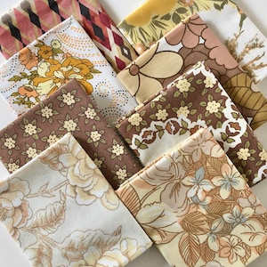 May include: A set of eight fabric squares featuring a variety of floral and geometric patterns in shades of brown, beige, and yellow. The fabrics are ideal for quilting, crafting, or home décor projects.
