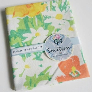 May include: A white fabric with a floral print in shades of yellow, green, and orange. The fabric is labelled "Vintage Fabric Fat 1/4" and "Get Smitten by Lisa Pocklington".