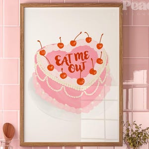 May include: A pink heart-shaped cake with white frosting and red cherries on top. The cake has the words "EAT ME OUT" written in red frosting.