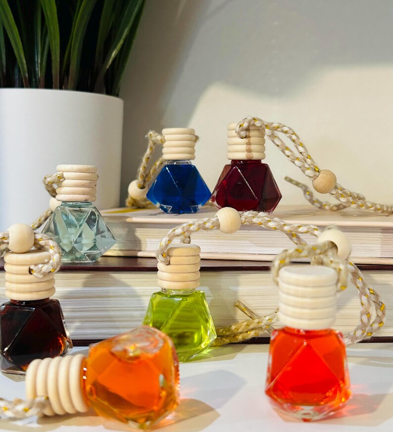 May include: Six diamond-shaped glass bottles with wooden tops and string hangers. The bottles are filled with colorful liquids, including red, blue, green, orange, and clear.