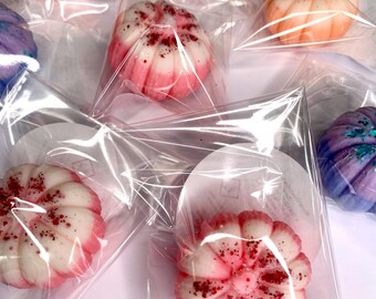 May include: A selection of pumpkin-shaped wax melts in clear packaging. The melts are in shades of pink, orange, and purple, some with glitter or speckled details. These decorative wax melts are designed for use with a wax warmer, adding fragrance to a room.