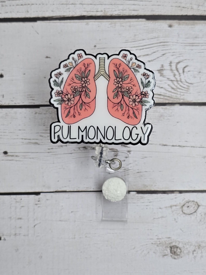 Puede incluir: Un dise&ntilde;o floral blanco y rosa de pulmones con la palabra "PULMONOLOGY" en texto negro. El dise&ntilde;o est&aacute; en un carrete de credencial transparente con una bola de purpurina blanca.