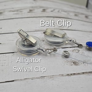 Puede incluir: Un portagafete retr&aacute;ctil transparente con un clip giratorio de cocodrilo plateado y un clip de cintur&oacute;n plateado. El portagafete tiene una correa de pl&aacute;stico transparente y un strass azul en el extremo.