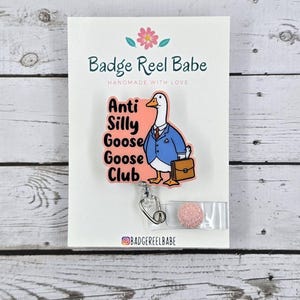 May include: A pink and white badge reel with a cartoon goose wearing a blue suit and holding a briefcase. The text on the badge reel says "Anti Silly Goose Club".