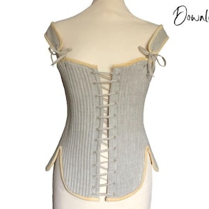 May include: A grey and white corset with a cream-coloured trim and a lace-up front. The corset is on a white mannequin.