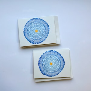 Op de afbeelding: Twee blanco wenskaarten met blauwe en gele cirkelvormige ontwerpen. De kaarten liggen op elkaar.