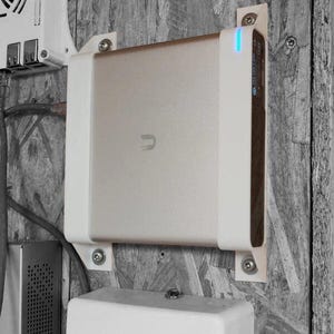 May include: A white hard drive with a white plastic enclosure mounted to a wall with screws. The hard drive has a blue light on the front. The hard drive is labelled "Seagate" and has a USB-C port.