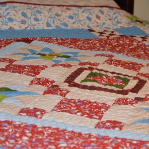May include: A patchwork quilt with a variety of colors and patterns, including red, blue, green, and white. The quilt is made up of squares and triangles, and it has a quilted texture.