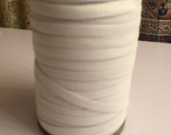 May include: A spool of white elastic band, wound tightly and ready for use in sewing or crafting projects.