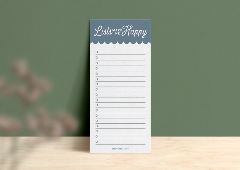 Pode incluir: Um bloco de notas azul com o texto "Lists Make Me Happy" no topo. O bloco de notas tem uma borda festonada e um fundo branco com linhas e caixas de sele&ccedil;&atilde;o.