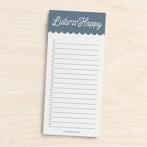 Pode incluir: Um bloco de notas azul com o texto "Lists Make Me Happy" no topo. O bloco de notas tem uma borda festoneada e um interior branco com linhas.