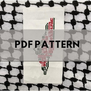 Op de afbeelding: Een kruissteekpatroon van de Palestijnse vlag, met de kleuren rood, groen, zwart en wit. Het patroon is op een witte achtergrond en wordt omringd door een zwart-wit geblokt doek.