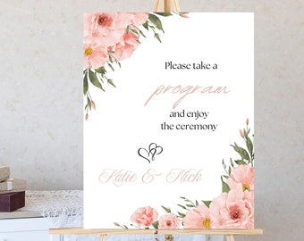 Peut inclure: Une pancarte de cérémonie de mariage blanche avec des accents floraux roses. La pancarte indique "Veuillez prendre un programme et profiter de la cérémonie" et "Katie & Nick".