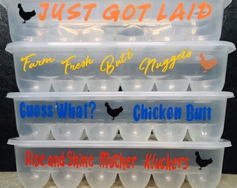 May include: Four clear plastic egg cartons stacked on top of each other. Each carton has a different humorous phrase written on it. The top carton says "JUST GOT LAID". The second carton says "Farm Fresh Butt Nuggets". The third carton says "Guess What? Chicken Butt". The bottom carton says "Rise and Shine Mother Kluckers".