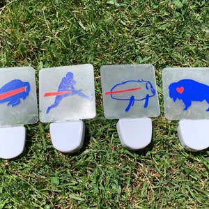 May include: Four white night lights with blue and red Buffalo Bills logos. The logos include a buffalo, a football player, a buffalo with a red stripe, and a buffalo with a red heart.