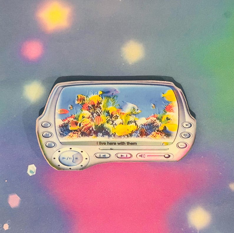 May include: A blue and white digital media player with a screen displaying a colorful underwater scene with fish and coral. The text "I live here with them" is displayed on the screen.