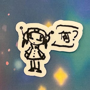 May include: A black and white sticker featuring a cartoon character in a space-themed outfit. The character has a helmet with antennae and a coat with buttons. A speech bubble next to the character contains Japanese text.