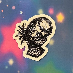May include: A black and white sticker featuring a scribbled illustration of a head with a wide grin and spiky hair. The artwork has a raw, expressive style, with visible pen strokes. The sticker is on a background with a mix of pink, blue, and yellow colors.
