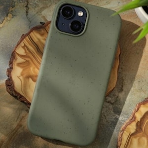 May include: A matte olive green smartphone case with a subtle speckled texture. The case features a raised rectangular camera cutout at the top left, housing two circular camera lenses and a small flash, designed for a modern mobile device.