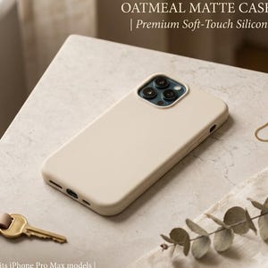Puede incluir: Una funda de teléfono mate color avena hecha de silicona suave al tacto para modelos iPhone Pro Max. La funda es de color beige con un recorte para las lentes de la cámara. El texto dice: OATMEAL MATTE CASE | Premium Soft-Touch Silicone.