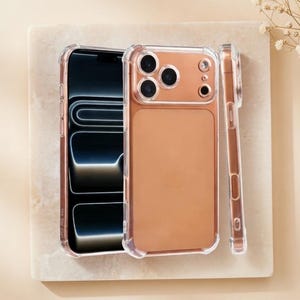 Puede incluir: Funda transparente para teléfono con parte trasera en oro rosa y bordes transparentes. La funda se muestra con un teléfono dentro y una funda separada de pie. La pantalla del teléfono es negra con un diseño azul claro.