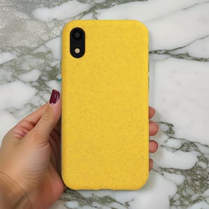 Op de afbeelding: Een gele telefoonhoes van gerecyclede materialen. De hoes heeft een textuur en een zwarte uitsparing voor de camera.