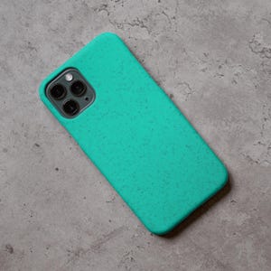 Puede incluir: Una funda de tel&eacute;fono turquesa con una textura moteada, dise&ntilde;ada para un tel&eacute;fono inteligente. La funda tiene un recorte para la c&aacute;mara y un dise&ntilde;o suave y redondeado. La funda est&aacute; hecha de un material duradero.