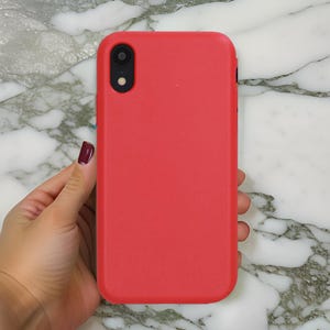 Op de afbeelding: Een felrode siliconen telefoonhoesje voor een smartphone met een enkele camera lens.