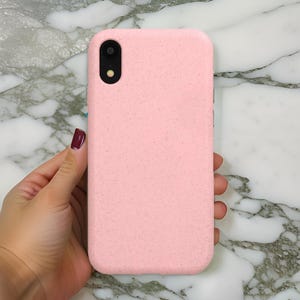Op de afbeelding: Een roze telefoonhoesje gemaakt van gerecyclede materialen. Het hoesje heeft een textuur en een uitsparing voor de camera.