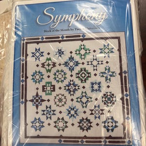 May include: A blue and white quilt pattern titled "Symphony" by Tucker University. The quilt design features various star patterns in shades of blue, green, and brown. The package is labeled as a 13-Month Program.