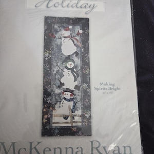 Puede incluir: Un kit de manualidades con temática de vacaciones de invierno, que presenta un diseño de tres muñecos de nieve en una escena nevada. El texto "Holiday" y "Making Spirits Bright" son visibles. Dimensiones: 40 cm x 102 cm.