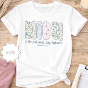 May include: White t-shirt featuring the word "NICU" in a floral and plaid design. The text "little patients, big futures" and Jeremiah 29:11 are printed below. The shirt is knotted at the bottom.