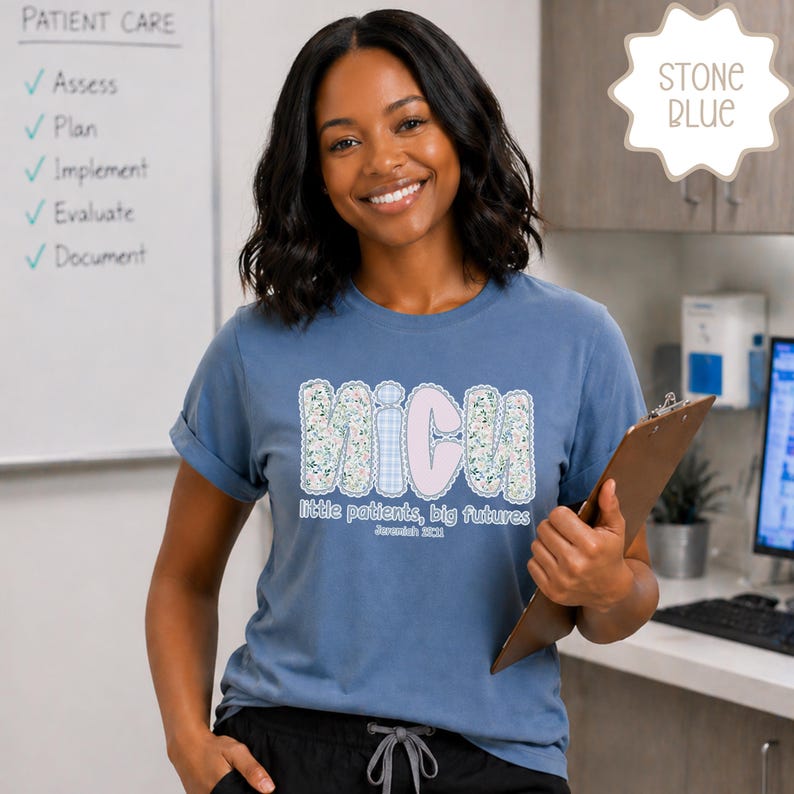 May include: A stone blue t-shirt with the letters "MICU" in a floral and gingham design. The shirt also features the text "little patients, big futures" and "Jeremiah 29:11". A woman is holding a clipboard.