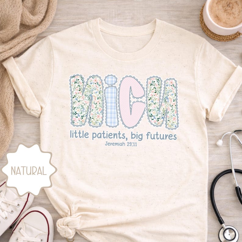 May include: Cream-coloured t-shirt with the word "NICU" in large, decorative letters. The letters are in a floral pattern and light blue gingham. The text "little patients, big futures" and Jeremiah 29:11 are below the letters.
