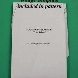 以下が含まれることがあります： 「Full Size Wedge Template included in pattern」と「COUNTRY STRINGS Tree Skirt」の文字が入った、ツリースカート用の白い紙のパターン。説明には、モスリンから12個のウェッジをカットするように書かれています。