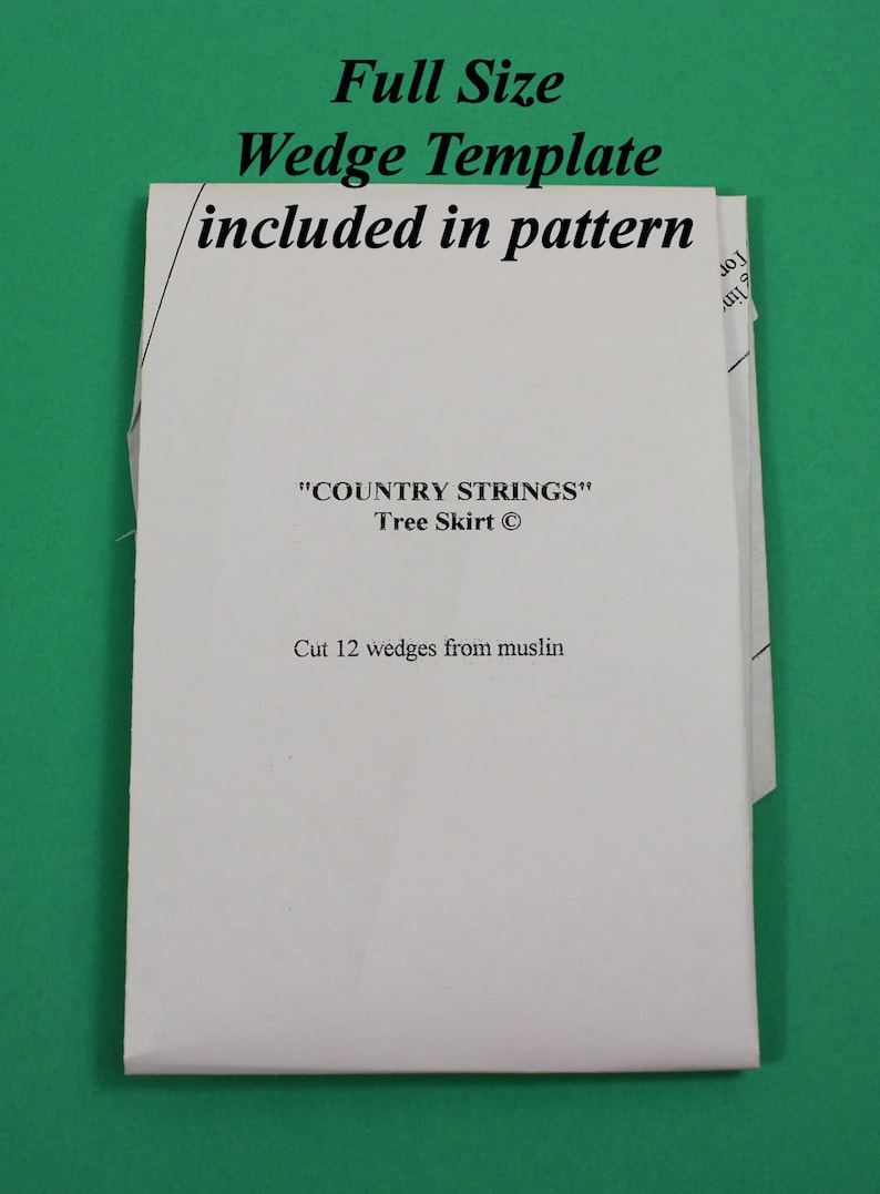 以下が含まれることがあります： 「Full Size Wedge Template included in pattern」と「COUNTRY STRINGS Tree Skirt」の文字が入った、ツリースカート用の白い紙のパターン。説明には、モスリンから12個のウェッジをカットするように書かれています。
