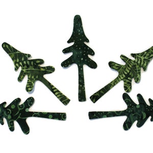 May include: Six green fabric Christmas tree ornaments with a white and green pattern. The ornaments are shaped like stylized pine trees.