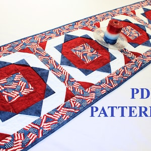 May include: A red, white and blue quilted table runner with a starburst pattern. The runner has a border of American flags. The text "PDF PATTERN" is visible in the bottom right corner of the image.