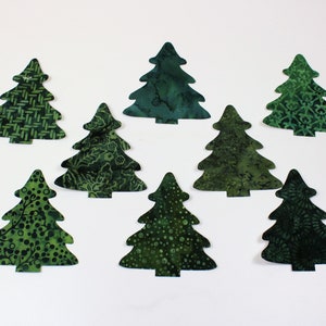 May include: Eight green fabric Christmas tree ornaments with different patterns.